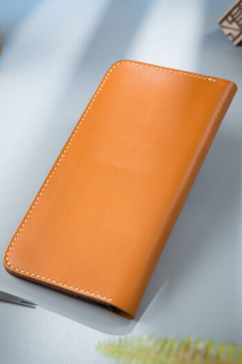 Long Wallet in serene Orange shade placed on Grey surface - Best MUSHI Wallet in Pakistan